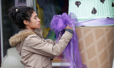Ingrid Sievers ties a ribbon in front of an ice cream shop on April 26 as officials investigate the homicide.