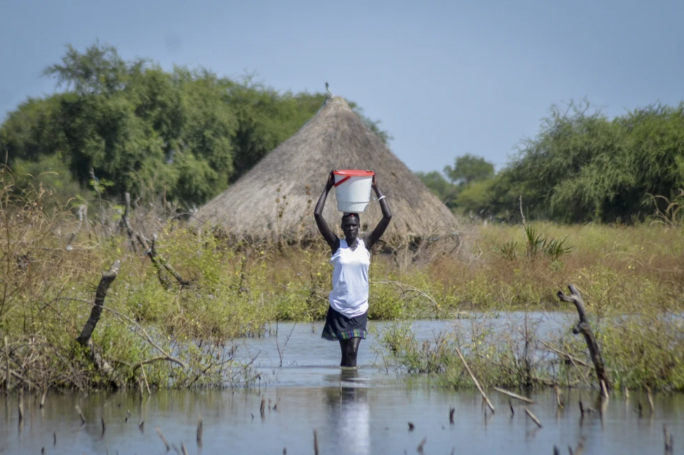 A woman carries a bucket on her head as she wades through floodwaters in the village of Wang Chot, Old Fangak county, Jonglei state, South Sudan, on Nov. 26, 2020.