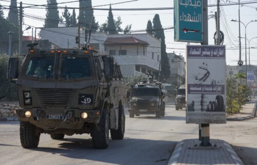 Israeli army vehicles drive down a road during a raid in Qabatiya