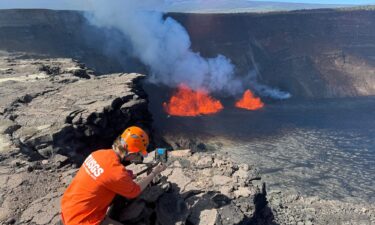 A U.S. Geological Survey Hawaiian Volcano Observatory geologist checks a webcam located on the rim of the caldera during a new eruption that began early at the Kilauea volcano in Hawaii on December 23.