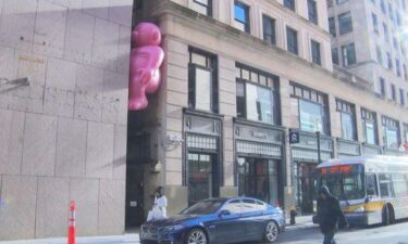 Giant pink people peering into restaurant windows and hanging out in alleyways.