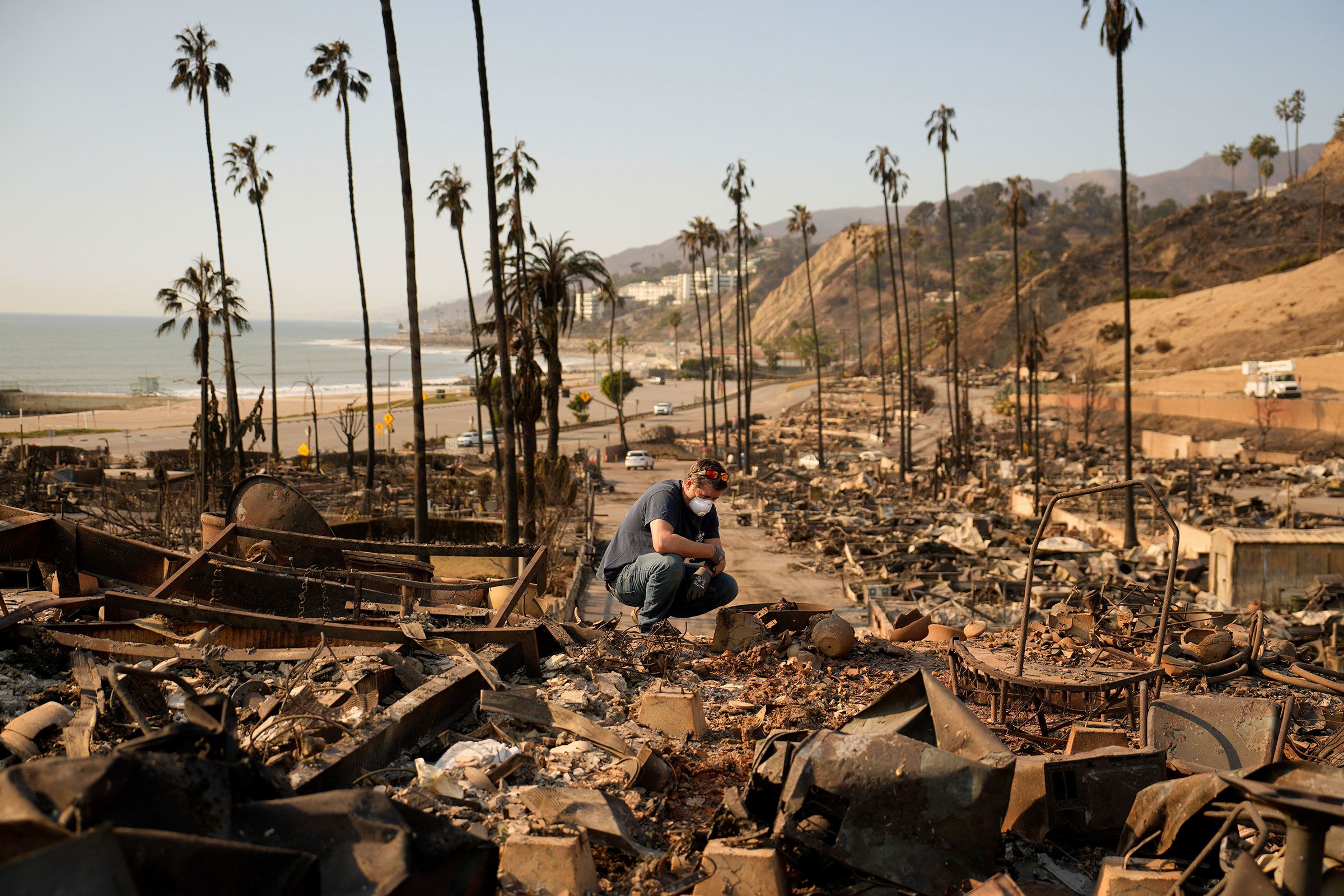 <i>John Locher/AP via CNN Newsource</i><br/>Kevin Marshall sifts through his mother's fire-ravaged property in the Pacific Palisades neighborhood of Los Angeles on January 11.