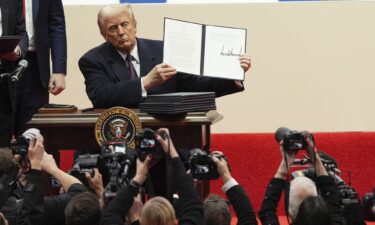 President Donald Trump holds up an executive order after signing it at an indoor Presidential Inauguration parade event in Washington