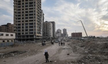 Displaced Palestinians pass destroyed buildings as they return to the north from the southern Gaza Strip on January 28.