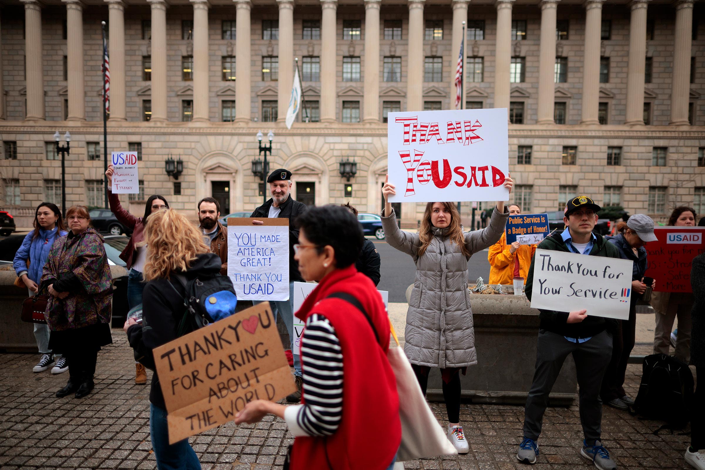 <i>Chip Somodevilla/Getty Images via CNN Newsource</i><br/>Supporters hold signs as former US Agency for International Development employees on February 27