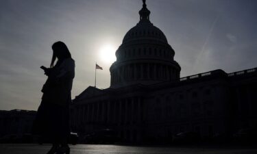 A person uses a mobile phone with the U.S. Capitol building in the background on Capitol Hill in Washington