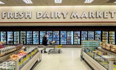 A shopper pushes a cart past the dairy section at a grocery store in Hamilton