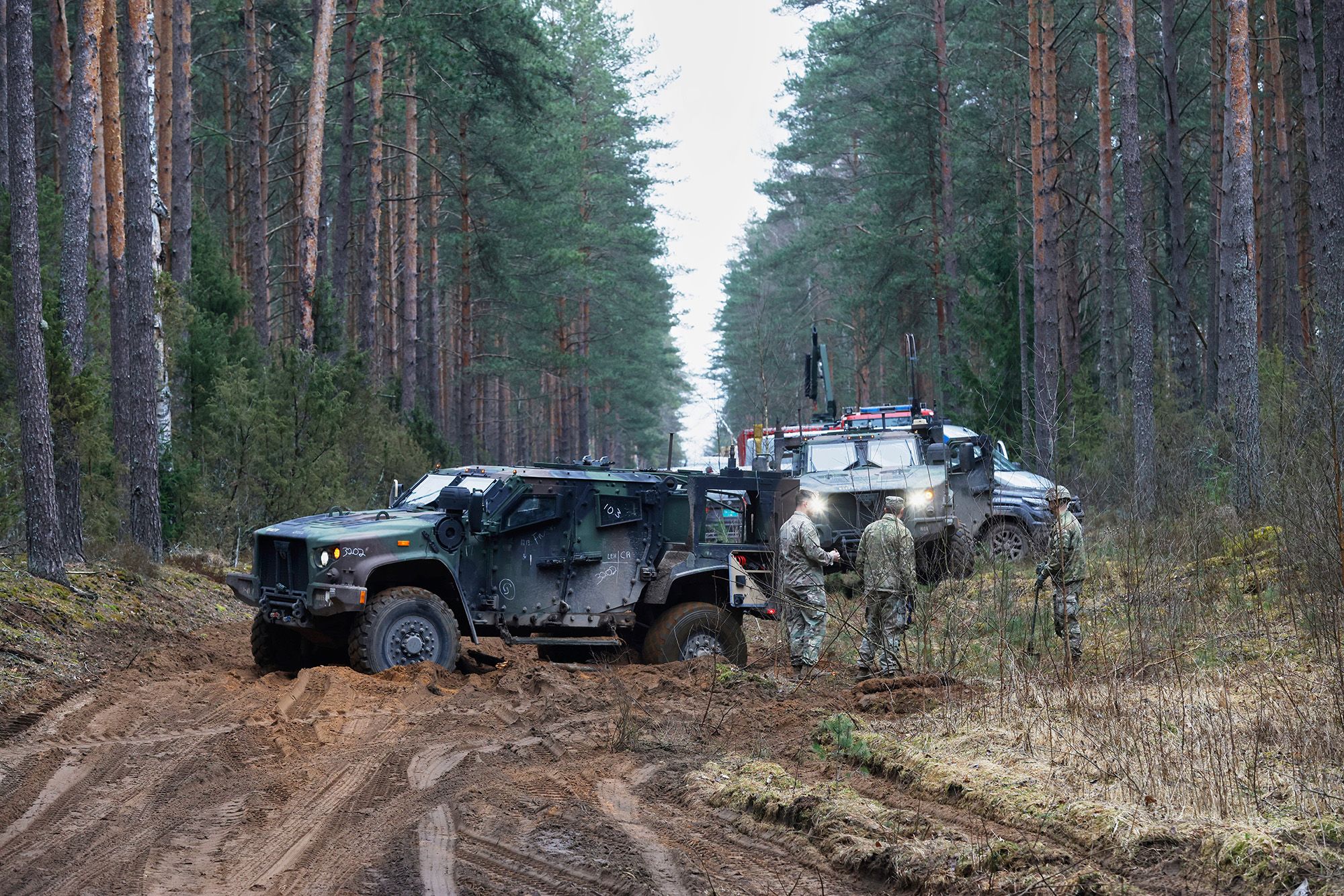 <i>Mindaugas Kulbis/AP via CNN Newsource</i><br/>U.S. soldiers stand near military vehicles parked at a training range in Pabrade