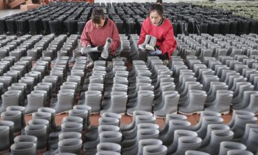 Employees check rain boots for export at a shoe factory in Lianyungang