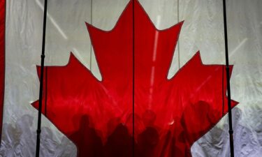 Supporters cast shadows on a Canadian flag as they gather prior to an election campaign event for Conservative Party of Canada's leader Pierre Poilievre in Vaughan