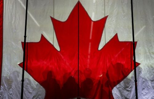 Supporters cast shadows on a Canadian flag as they gather prior to an election campaign event for Conservative Party of Canada's leader Pierre Poilievre in Vaughan