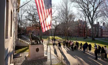 People take photos near a John Harvard statue on the Harvard University campus in Cambridge