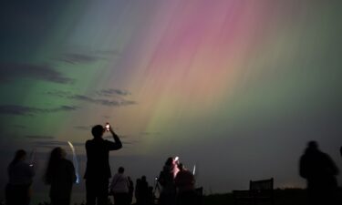 People observe northern lights over St. Mary's lighthouse in Whitley Bay on England's coast in May 2024.