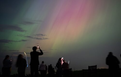People observe northern lights over St. Mary's lighthouse in Whitley Bay on England's coast in May 2024.