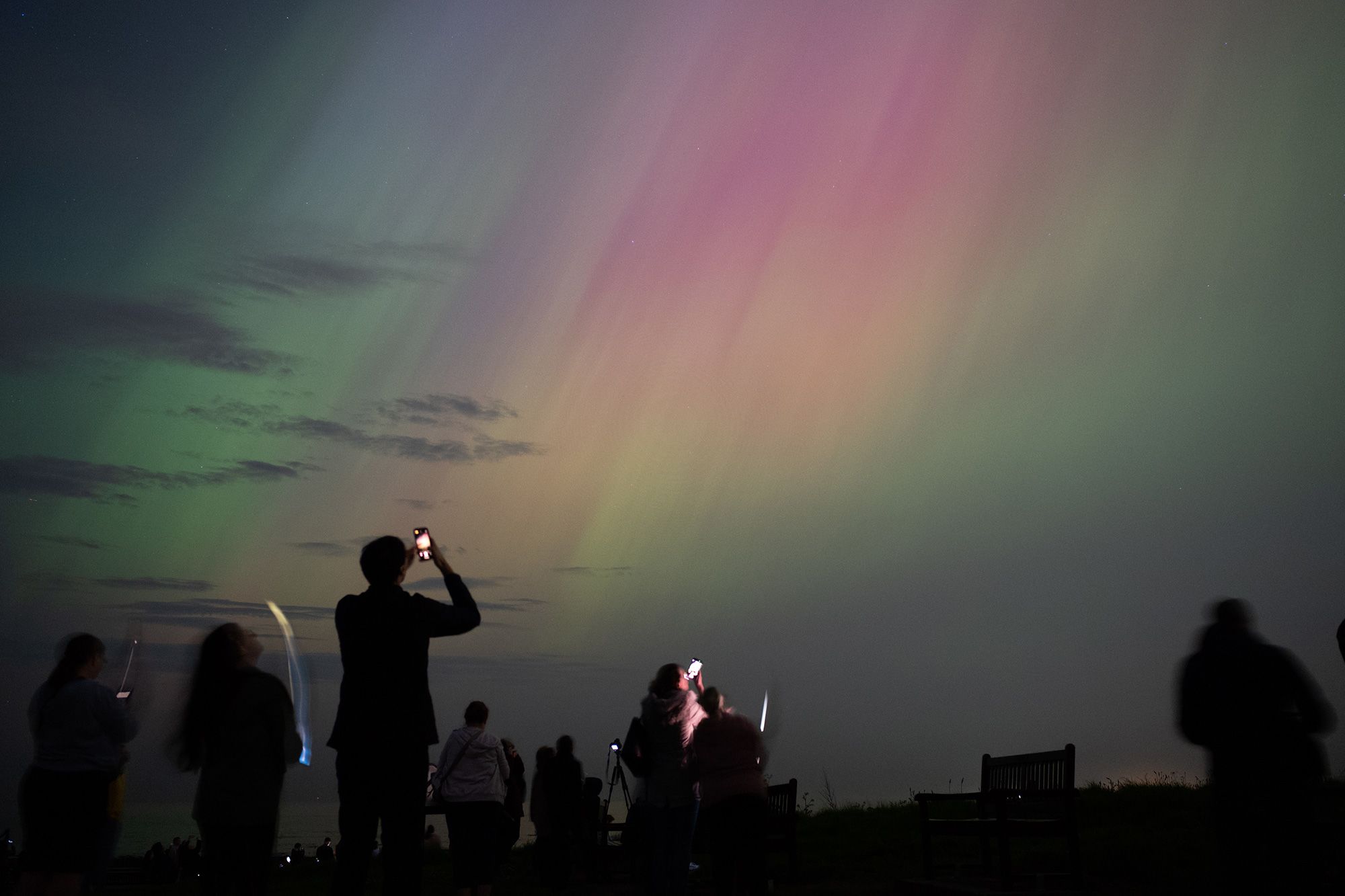 <i>Ian Forsyth/Getty Images via CNN Newsource</i><br/>People observe northern lights over St. Mary's lighthouse in Whitley Bay on England's coast in May 2024.