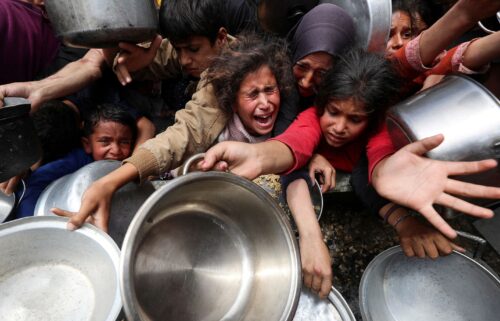 Palestinians wait to receive food cooked by a charity kitchen
