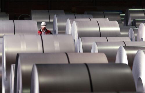 A worker walks among coils of finished steel at a plant in Duisburg