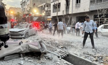 People and first-responders gather outside a building that was hit by an Israeli strike in Tehran on Friday