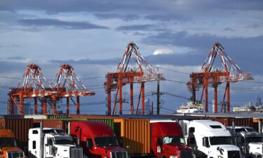 View of shipping cranes seen behind trucks and shipping containers at a port in Elizabeth
