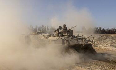 Israeli soldiers stand on an armored personnel carrier as they move near the border with the Gaza Strip as seen from a position on the Israeli side of the border