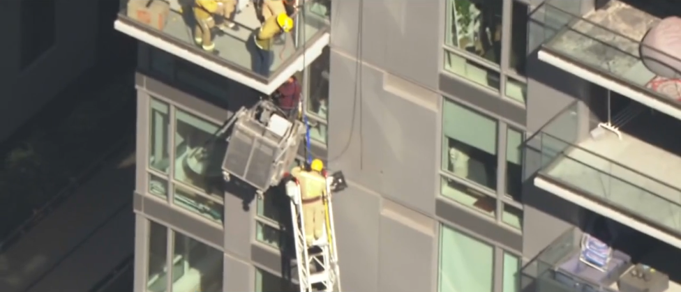 <i>KCAL/KCBS via CNN Newsource</i><br/>Firefighters rescued a window washer who was trapped several stories high on the side of a downtown Los Angeles high-rise apartment building on July 29.