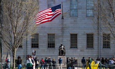 Demonstrators with signs stand around the John Harvard Statue in Harvard Yard after a rally was held against President Donald Trump's attacks on Harvard University at Harvard University in Cambridge