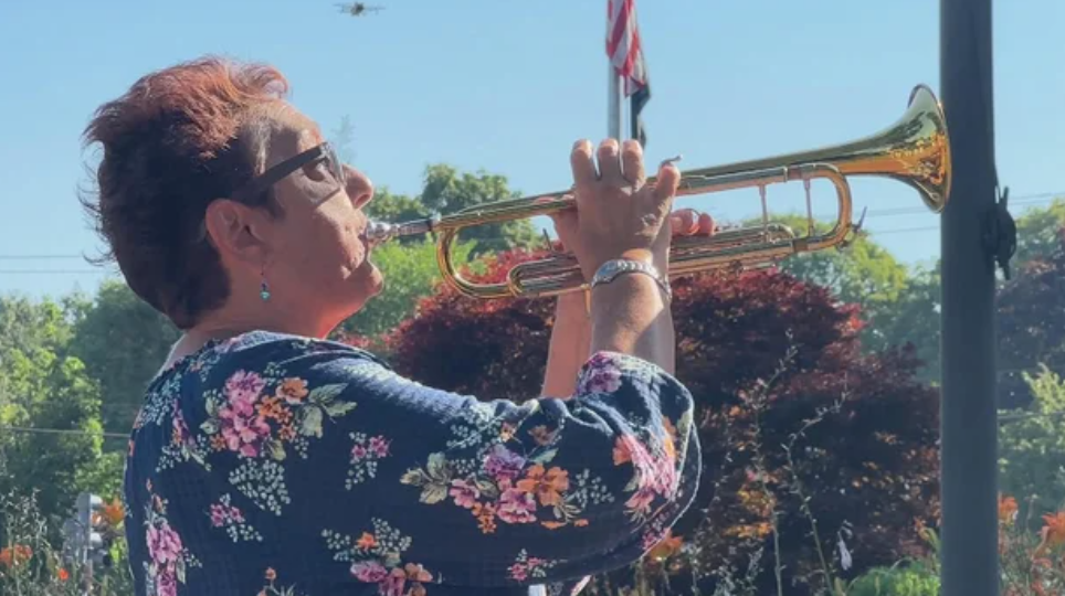 <i>WBZ via CNN Newsource</i><br/>Jenn Hozempa plays her trumpet at the town common in Franklin