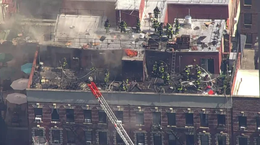 <i>WCBS/WLNY via CNN Newsource</i><br/>Firefighters battle a blaze on the roof of a building on East 95th Street on August 15.