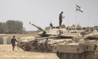 Israeli soldiers work near tanks in a gathering point near the border with the Gaza Strip