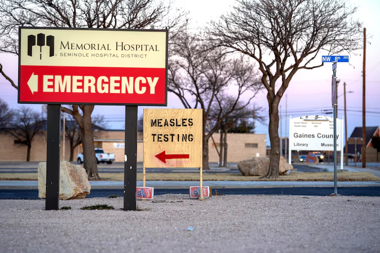 In this Feb. 27, 2025, file photo, signs point the way to measles testing in the parking lot of the Seminole Hospital District across from Wigwam Stadium, in Seminole, Texas.