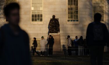 People gather to take photos with the John Harvard Statue at Harvard University in Cambridge