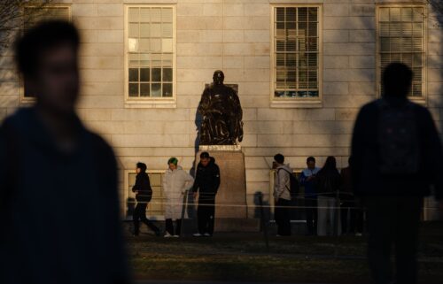People gather to take photos with the John Harvard Statue at Harvard University in Cambridge
