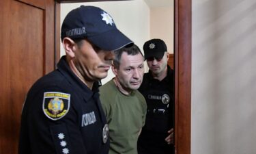 Police officers escort the suspect in the murder of Ukrainian lawmaker Andriy Parubiy into a courtroom in Lviv