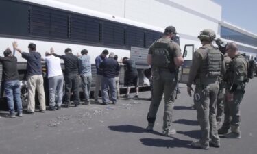 This image from video provided by US Immigration and Customs Enforcement shows manufacturing plant employees waiting to have their legs shackled at the Hyundai Motor Group’s electric vehicle plant