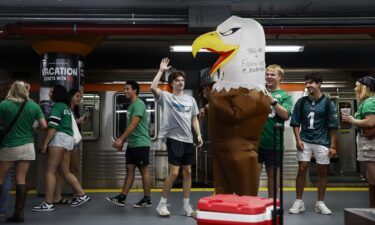 Eagles fans high five a person wearing an eagles costume as people exit the train inside NRG station before the Philadelphia Eagles game on September 4