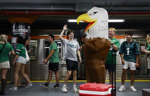 Eagles fans high five a person wearing an eagles costume as people exit the train inside NRG station before the Philadelphia Eagles game on September 4