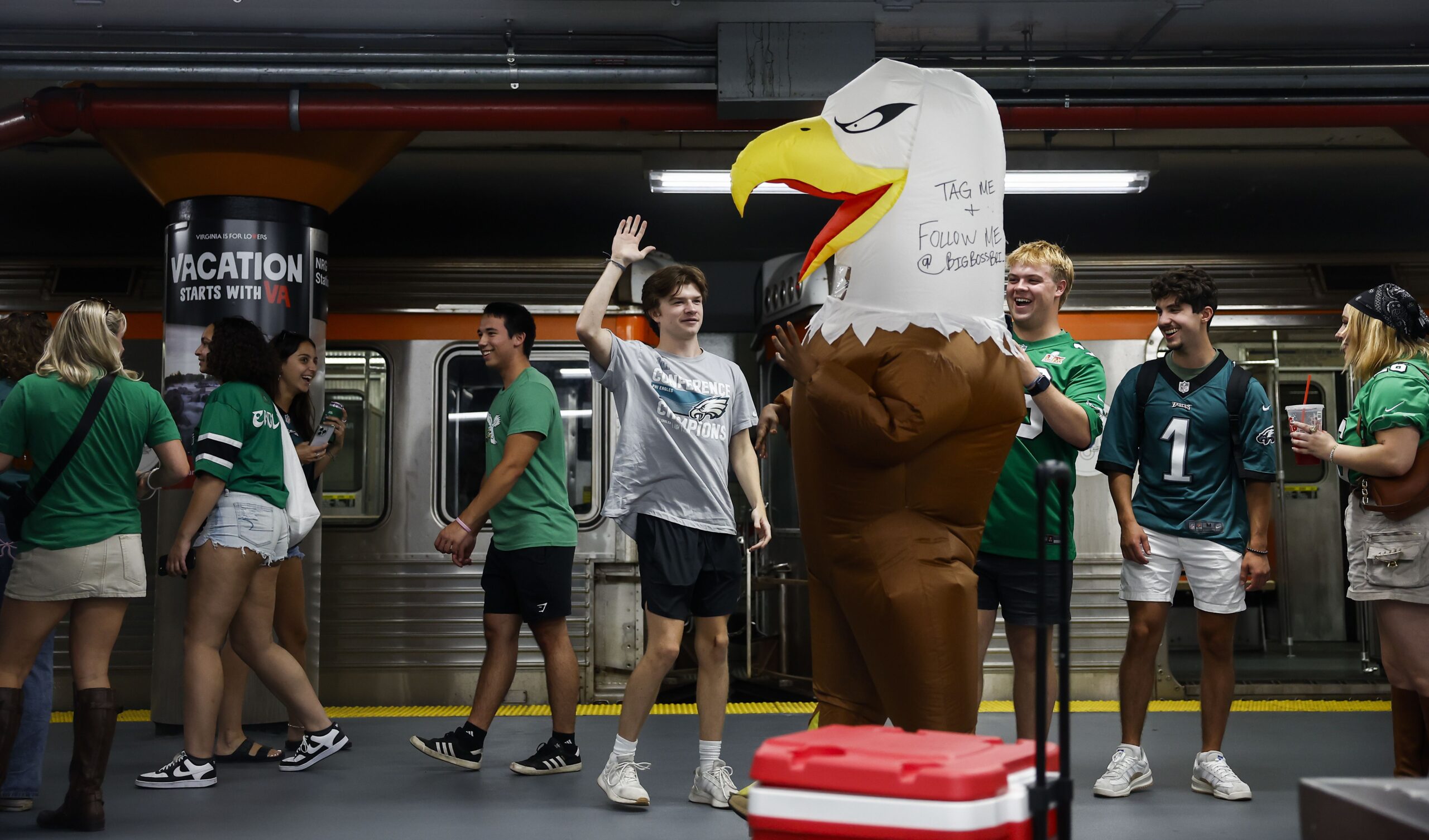 Eagles fans high five a person wearing an eagles costume as people exit the train inside NRG station before the Philadelphia Eagles game on September 4