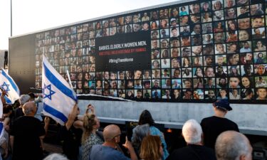 People stand near a wall covered with pictures of Israeli hostages during a demonstration against the Israeli government in the northern Israel city of Karmiel on July 25