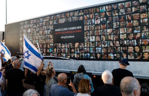 People stand near a wall covered with pictures of Israeli hostages during a demonstration against the Israeli government in the northern Israel city of Karmiel on July 25