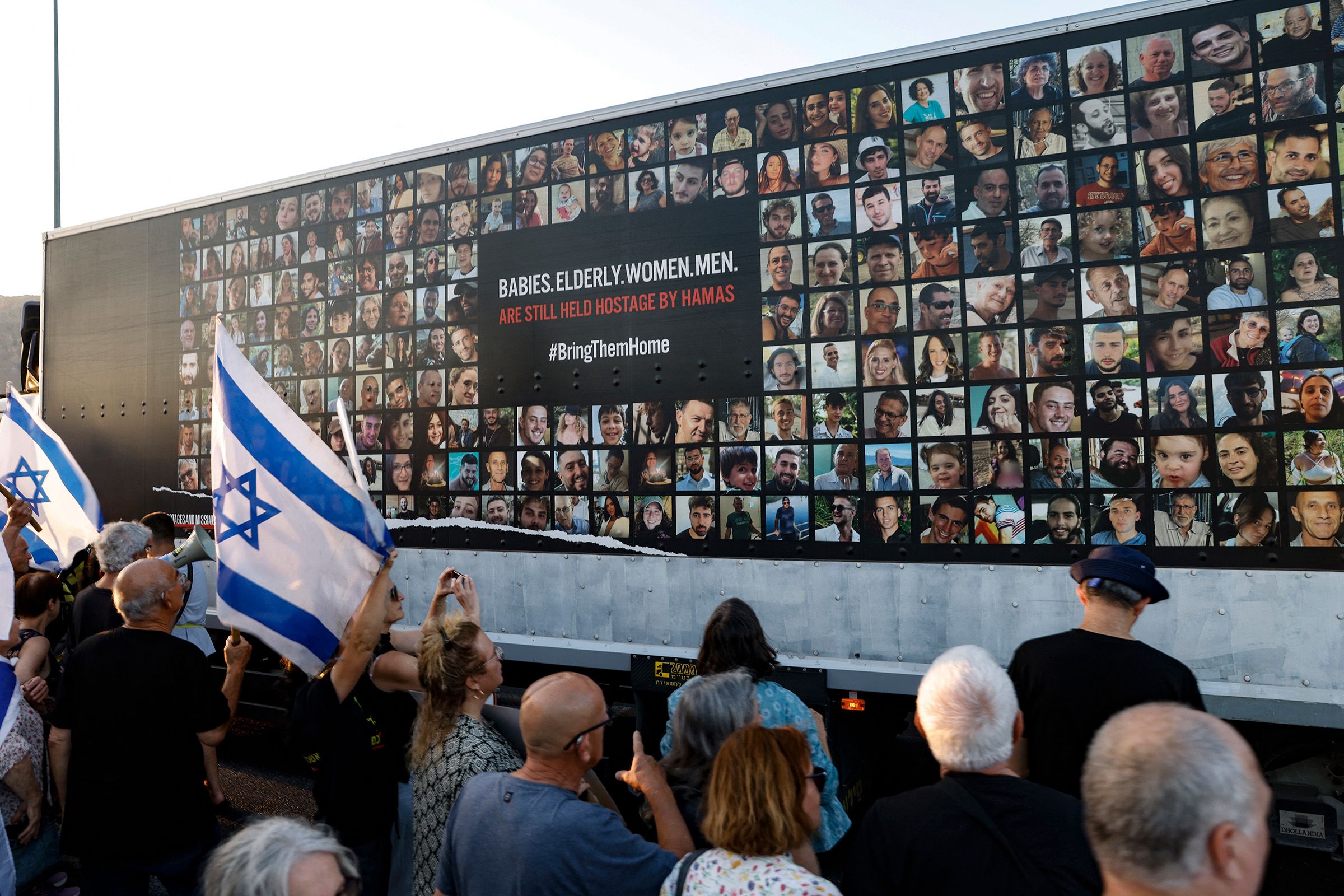 <i>Jalaa Marey/AFP/Getty Images via CNN Newsource</i><br/>People stand near a wall covered with pictures of Israeli hostages during a demonstration against the Israeli government in the northern Israel city of Karmiel on July 25