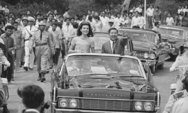 Jacqueline Kennedy and Chief of State Prince Norodom Sihanouk are cheered during a motorcade in Phnom Penh.