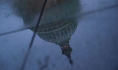 The US Capitol dome is reflected in a puddle on the ground