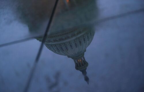 The US Capitol dome is reflected in a puddle on the ground