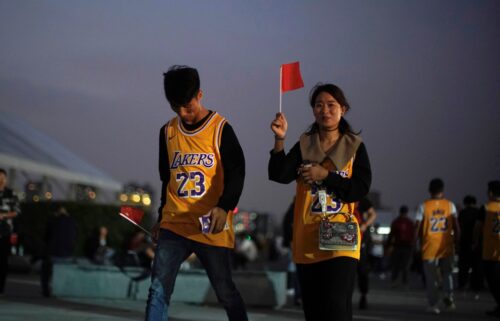 A woman and a man in LeBron James jerseys hold Chinese national flags before an NBA exhibition game between the Brooklyn Nets and Los Angeles Lakers in Shanghai in 2019.