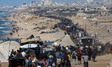Displaced Palestinians wave to the camera as they walk along the coastal road in the direction of Gaza City on October 10.