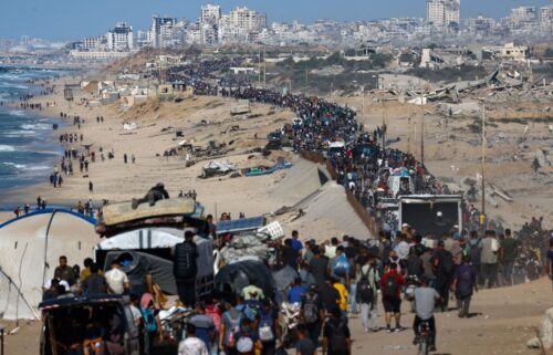 Displaced Palestinians wave to the camera as they walk along the coastal road in the direction of Gaza City on October 10.