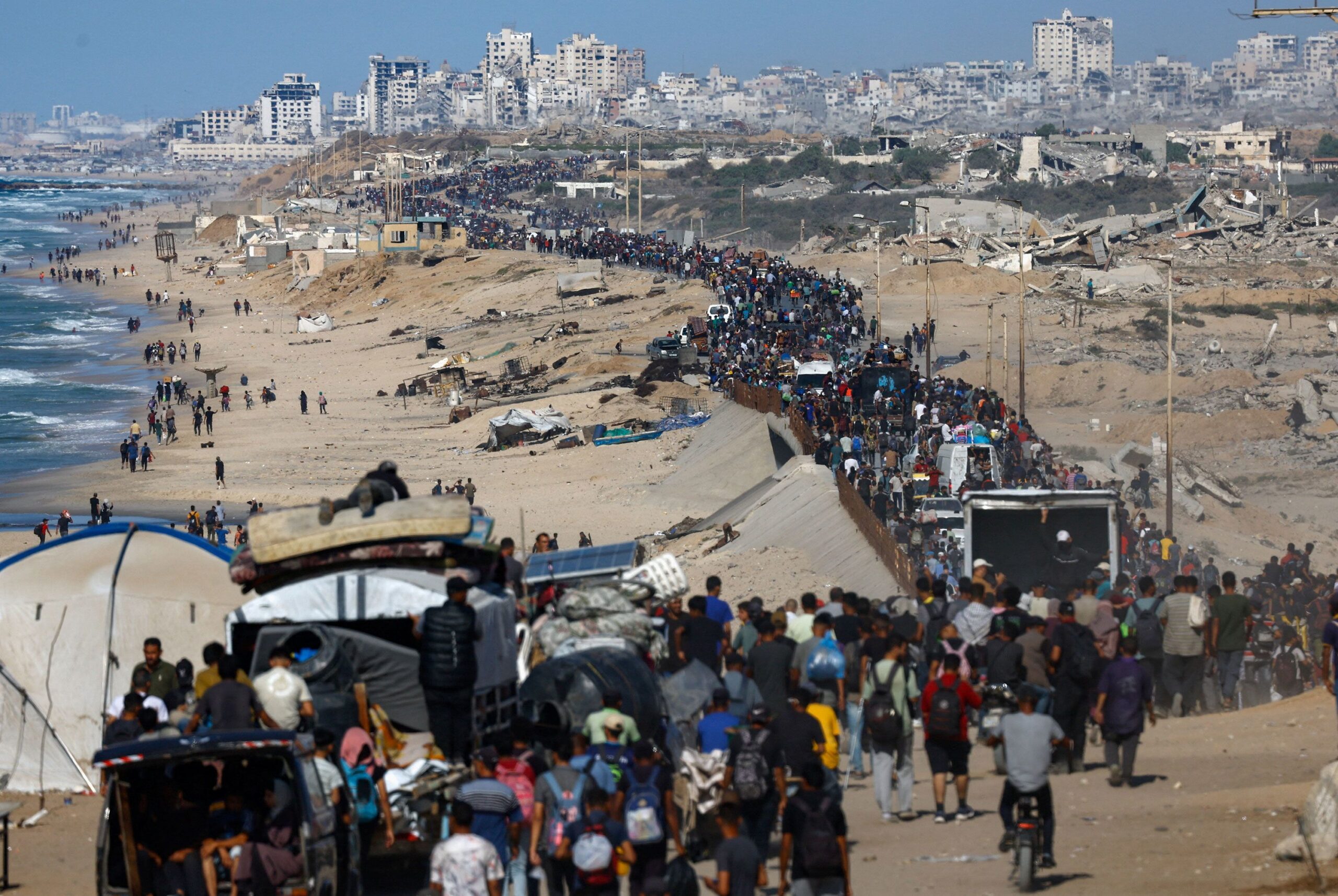 Displaced Palestinians wave to the camera as they walk along the coastal road in the direction of Gaza City on October 10.