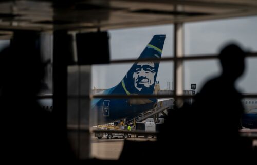 An Alaska Airlines plane past travelers at Ronald Reagan Washington National Airport in Arlington