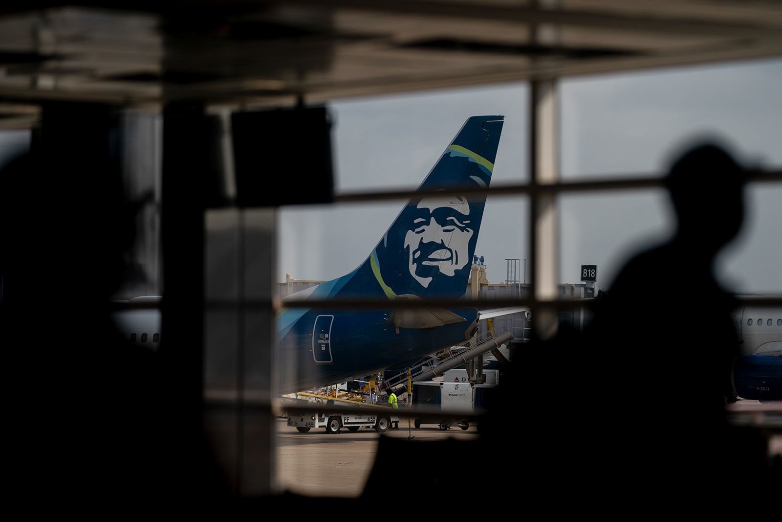 An Alaska Airlines plane past travelers at Ronald Reagan Washington National Airport in Arlington