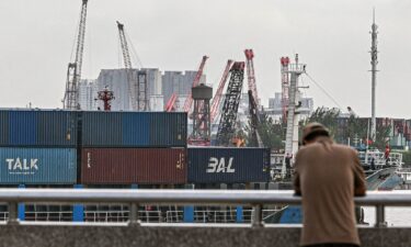 A man stands as a cargo ship carrying containers sails into a dock at a container terminal in Shanghai